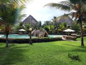 a resort with a swimming pool and a resort with palm trees at Tembo Beach Cottage , Ocean Beach Drive in Malindi