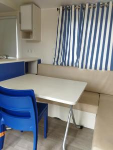 a small kitchen with a table and a blue chair at chalet 2 in Saint-Christol-lès-Alès