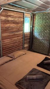 a room with a bed with a wooden wall at ALAMSUKA Cikole in Tangkubanperahu