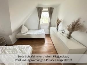 a white bedroom with a bed and a window at Moderne Ferienwohnung in Strandnähe - Urlaubsträume am Meer in Neue Tiefe Fehmarn