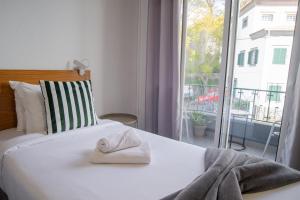 a bedroom with a white bed with a window at Mountain View Star in Estreito da Calheta