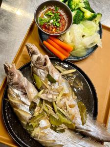 two plates of food with fish and vegetables on a tray at wooden tree nongkhai in Nong Khai +50 photos
