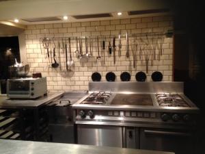 a kitchen with a stove and utensils on the wall at Guesthouse Maison de la Rose in Bruges