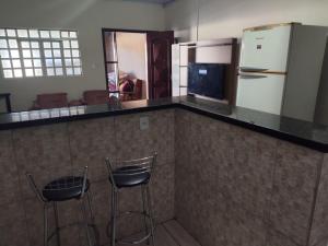 a kitchen with two bar stools and a refrigerator at Morada ind in Araguari