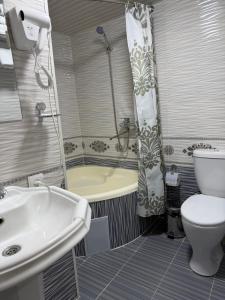 a bathroom with a tub and a toilet and a sink at Al-Adl Guest House in Bukhara