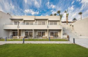 a white building with a lawn in front of it at V Hotel Sharm El Sheikh in Sharm El Sheikh