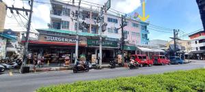 a busy city street with motorcycles driving past a building at Bedroom401 Kata Beach Phuket in Kata Beach +1 photo