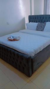 a large bed with a black frame with a blanket on it at Amani Home in Kisii