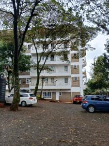 a large white building with cars parked in a parking lot at Amani Home in Kisii