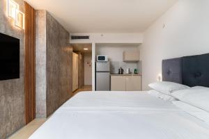 a bedroom with a large white bed and a kitchen at Netanya SeaView ApartHotel in Netanya