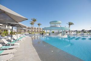 a swimming pool with lounge chairs and a building at V Hotel Sharm El Sheikh in Sharm El Sheikh