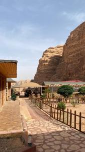 a building with a fence next to a mountain at Golden Camp- wadi rum in Wadi Rum