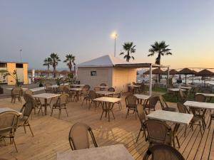 an outdoor patio with tables and chairs and palm trees at Aparthotel Codex in Rossano