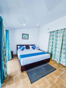 a bedroom with a bed with blue curtains and a wooden floor at The Valley View Homestay in Lansdowne