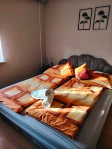 a unmade bed with a comforter and pillows at HeuReka Apartman in Pécs