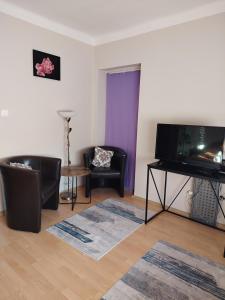 a living room with two chairs and a flat screen tv at HeuReka Apartman in Pécs