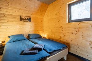 a bed in a log cabin with a window at Barn&Haus-Stodoły Widokowe in Zubrzyca Dolna
