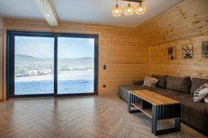 a living room with a couch and a large window at Barn&Haus-Stodoły Widokowe in Zubrzyca Dolna