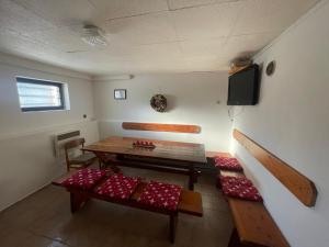 a room with a table and benches and a tv at Chata Hella in Pernink