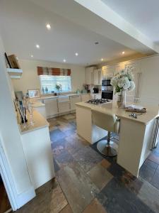 a large kitchen with white cabinets and a table at The Cherries in Penrhyn Bay