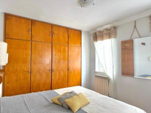 a bedroom with a bed and wooden cabinets at Casa Eugenia in Sesimbra