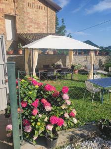 ein weißer Sonnenschirm, einige rosa Blumen und ein Tisch in der Unterkunft Bb Casolara2 in San Giovanni