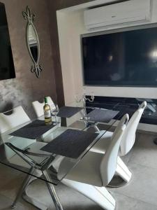 a glass table with white chairs and a large television at Sea views-Balcony-Sleeps 6-Parking-AirCon Heating in Daimuz +3 photos