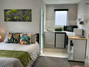 a small bedroom with a bed and a kitchen at Rivendell Holiday Studios & Suite in Swanage