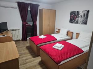 Zwei Betten in einem kleinen Zimmer mit roten Laken in der Unterkunft ViiLaEne in Deta
