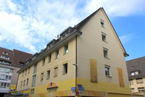 un bâtiment jaune avec un toit noir dans l'établissement City Hotel Freiburg, à Fribourg-en-Brisgau