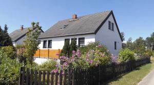 a white house with a fence and flowers at Strandgut- die Große in Dranske