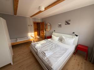 a bedroom with a white bed and a red chair at Strandgut- die Große in Dranske