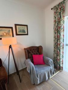 a living room with a brown chair with a pink pillow at Casa da Avó Virgínia in Elvas