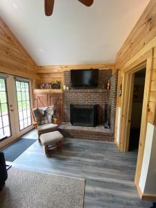 a living room with a fireplace and a tv at Cozy stream-side cabin in Lanesborough