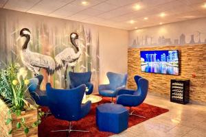 a waiting room with blue chairs and a mural of birds at Turmhotel Schwedt in Schwedt