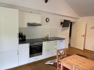 a kitchen with white cabinets and a sink and a table at Allgäu- Ferienwohnung mit Hund in Oberreute