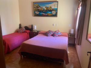 a bedroom with two beds and a painting on the wall at Cabañas Luna y Sol in Cafayate +22 photos