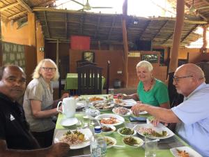 a group of people sitting around a table eating food at Sigiriya Melrose Villas in Sigiriya