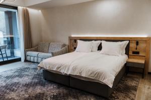 a bedroom with a large bed and a chair at Комплекс РАЙ in Ognyanovo