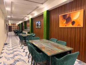 a dining room with tables and green chairs at Gulberg Inn Hotel Lahore in Lahore