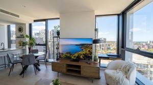 a living room with a large tv and a table and chairs at Domain House Executive in Melbourne