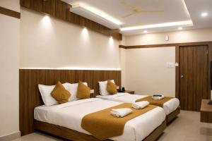 a hotel room with two beds with towels on them at Hotel Sakura Inn in Hosūr