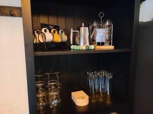 a black cabinet with glasses on a shelf at Loc Aquatropic appartement de vacances in Bevaix +20 photos