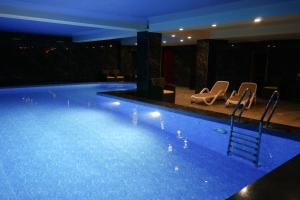 a large swimming pool with chairs in a building at Hotel Arai Plaza in Taraz