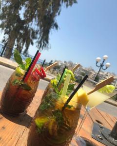 three drinks sitting on a wooden table on a table at By the wave luxurious studios in Piraeus