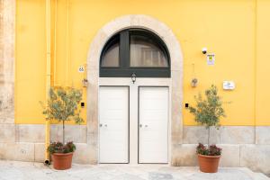 two white doors in front of a yellow building at Desideri di Puglia in Barletta