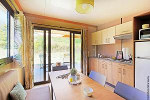 a kitchen with a wooden table and a dining room at Camping Les Lavandes in Darbres