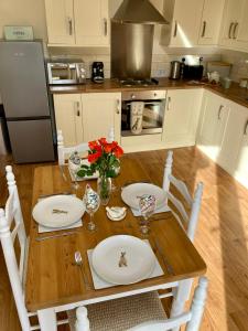 a kitchen with a wooden table with plates and flowers on it at The Stables in Metheringham