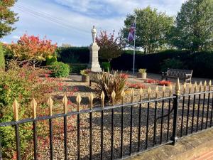a fence with a statue in the middle of a garden at The Stables in Metheringham