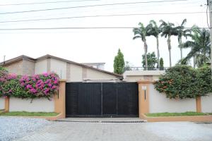 a black gate in front of a house with flowers at Petite's Nest - Apartment 5 in Accra